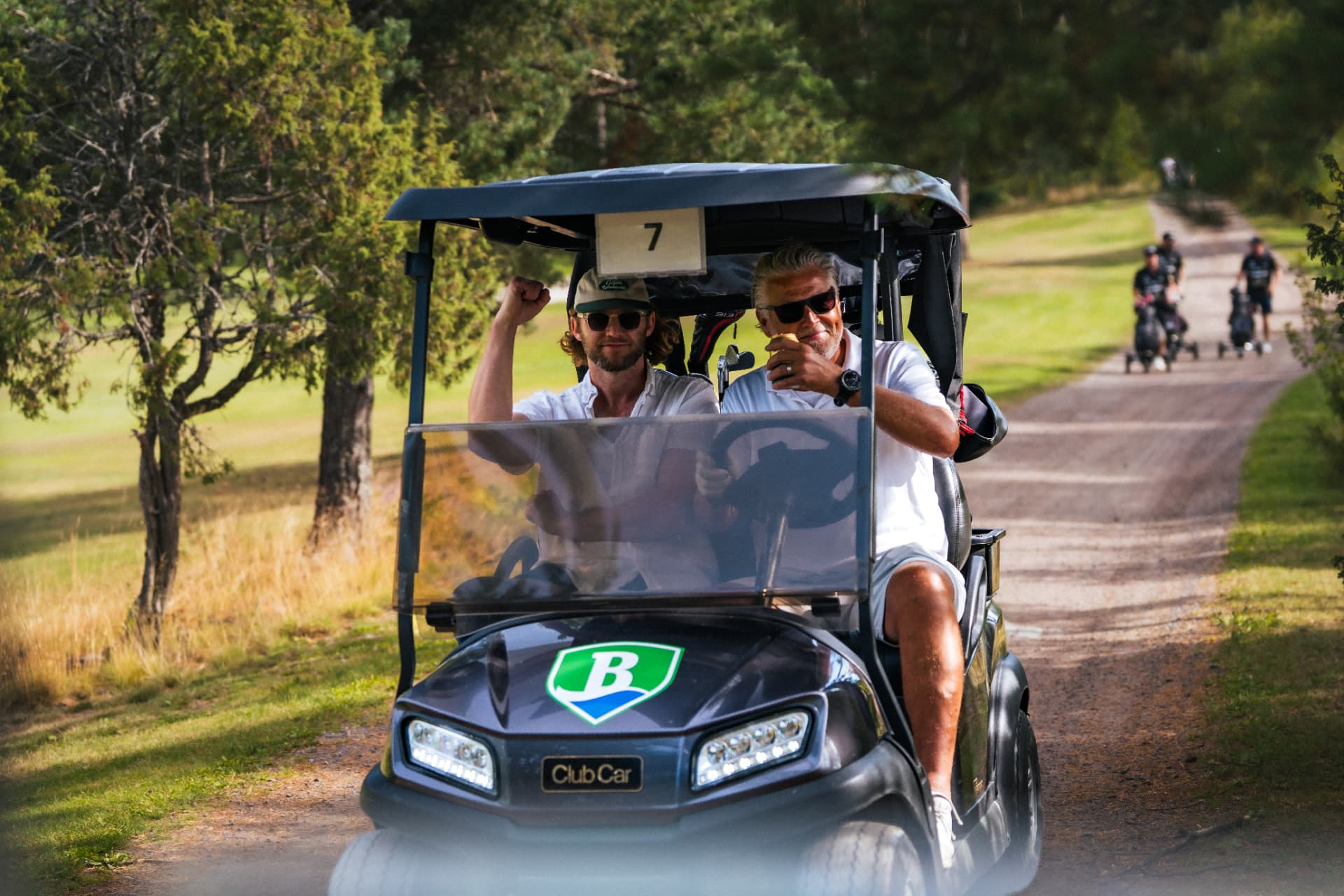 Två spelare i golfbil med Bryngfjordens logotyp