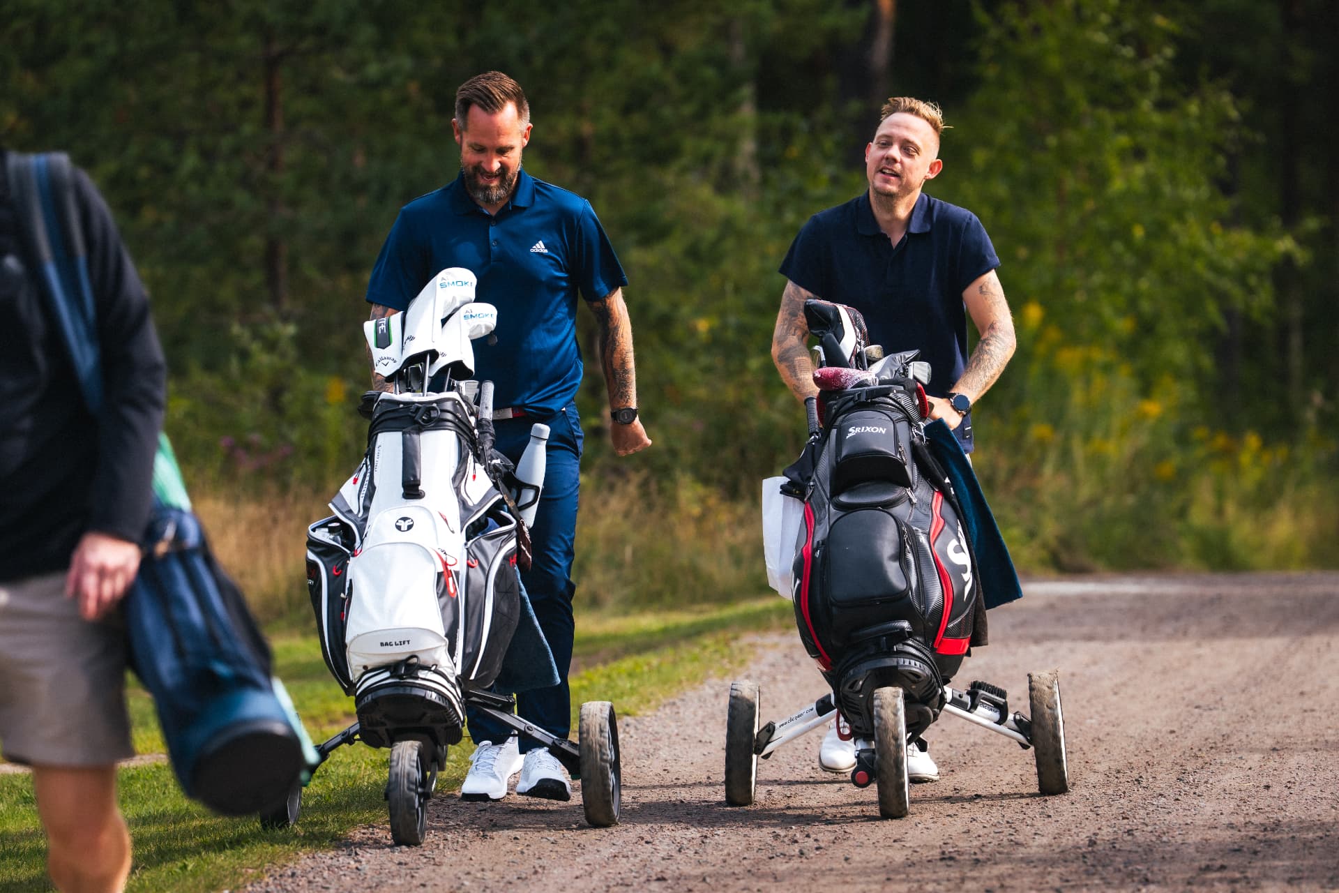 Två spelare med bagvagnar på grusvägen