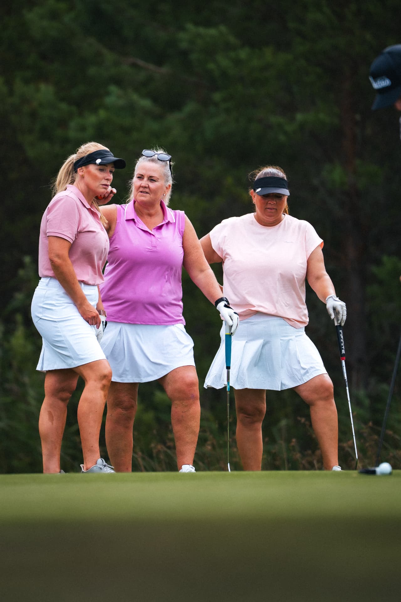 Tre spelare i rosa på greenen