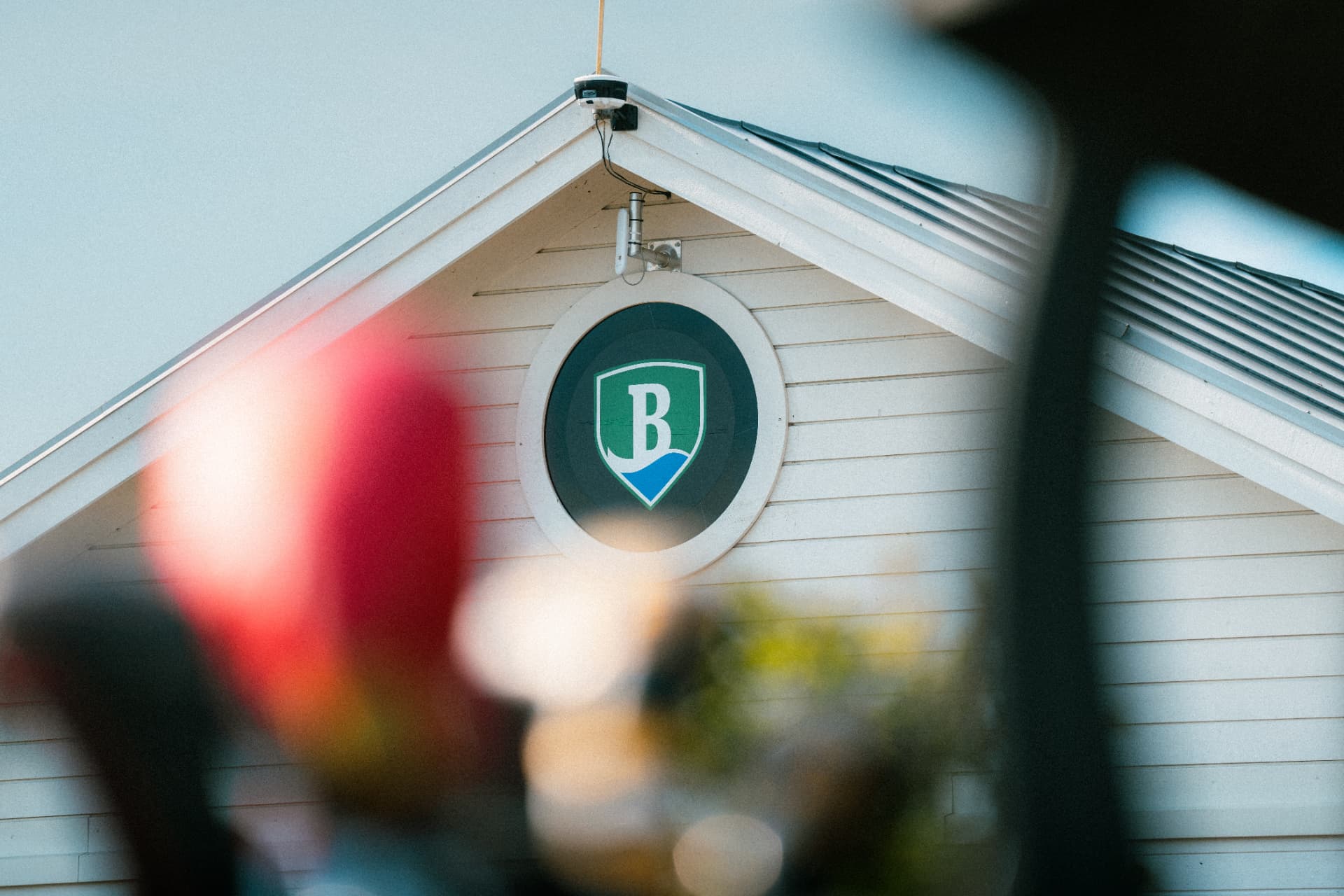 Klubbhusets logotyp sedd genom grenverk