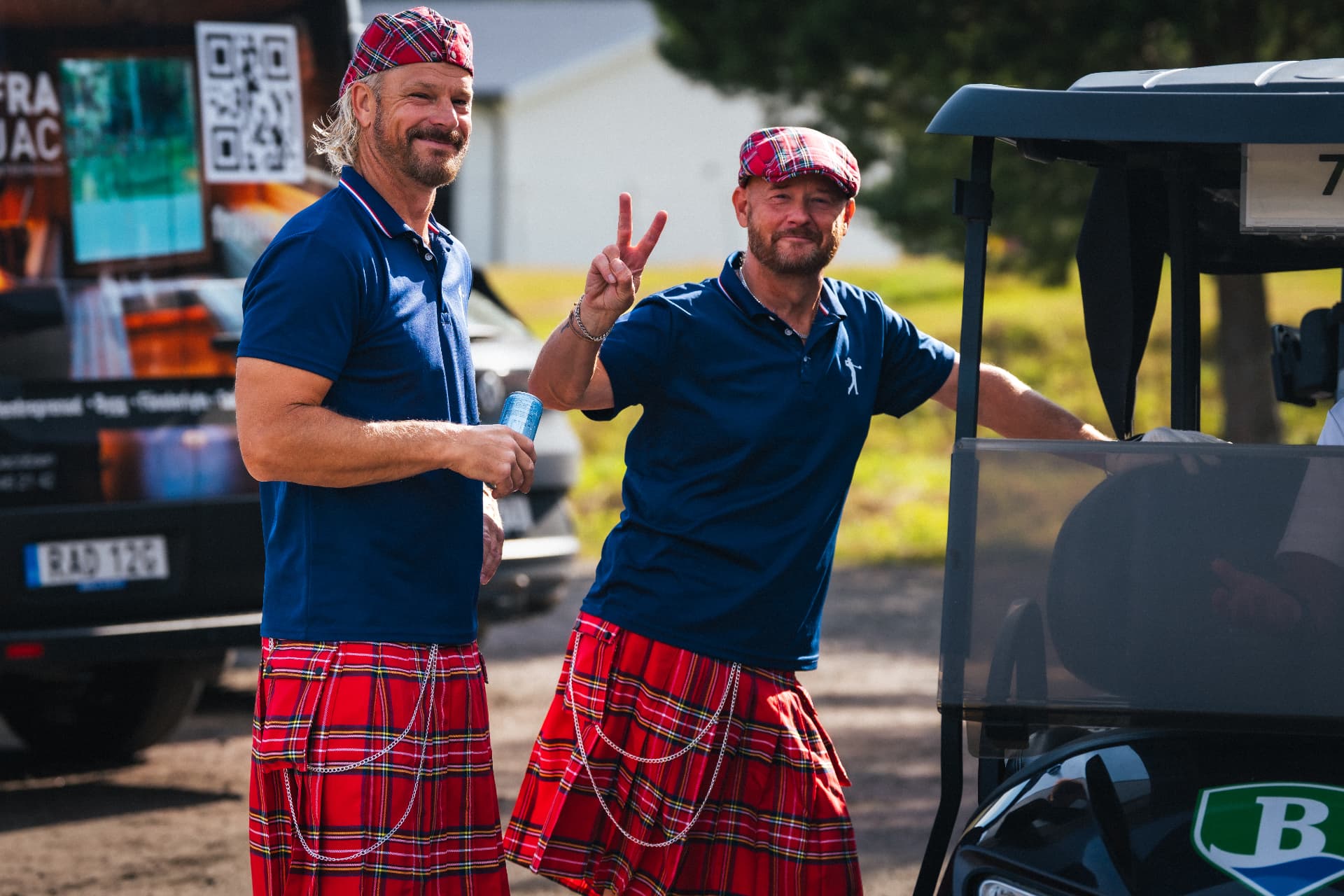 Två deltagare i kilt vid golfbilen