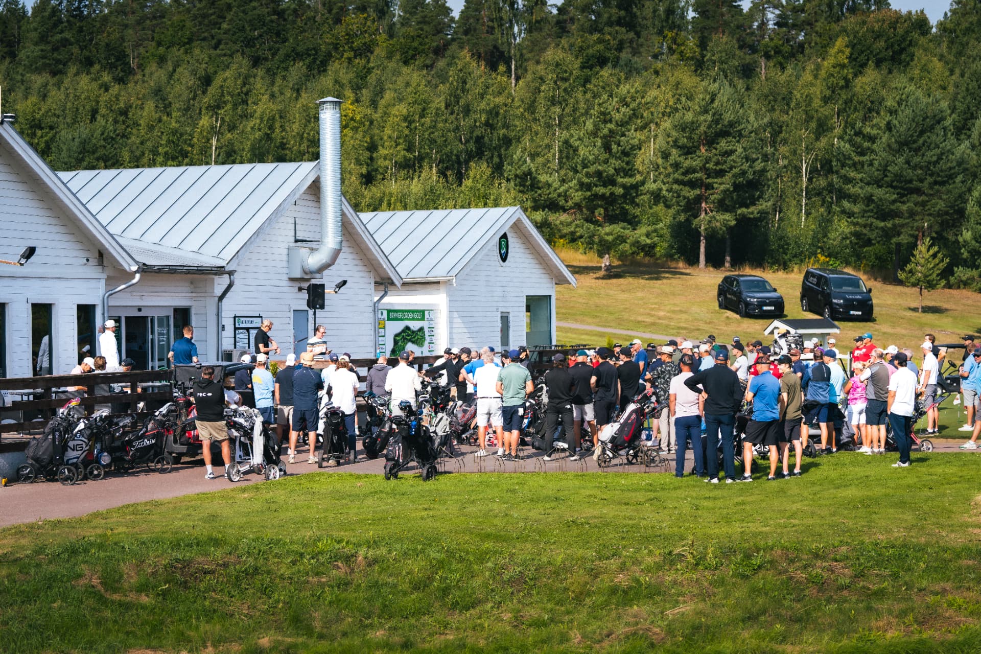 Deltagare samlade utanför klubbhuset i morgonsol