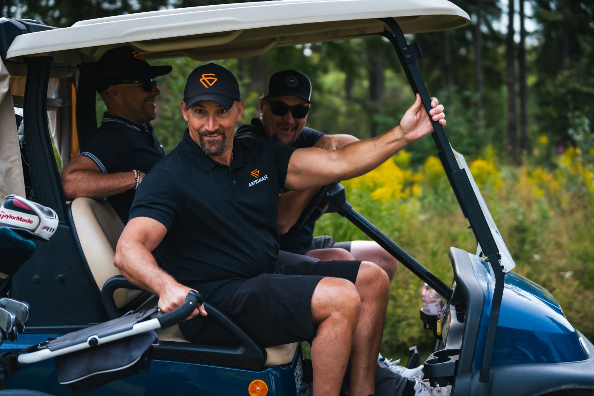 Tre spelare i golfbil på väg ut på banan