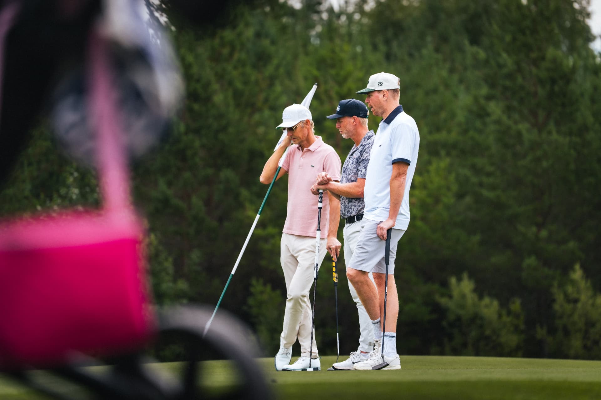 Tre spelare vid flaggan på greenen