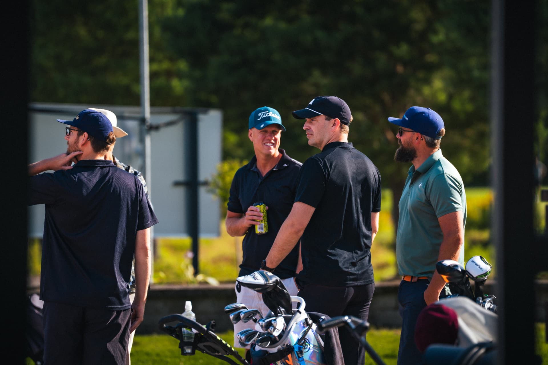 Fyra deltagare samtalar vid golfbagarna