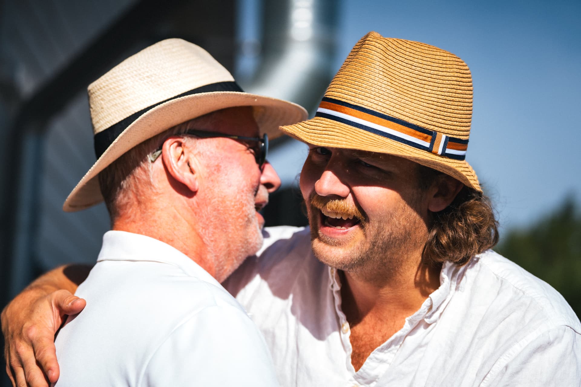 Två deltagare i sommarhattar kramas