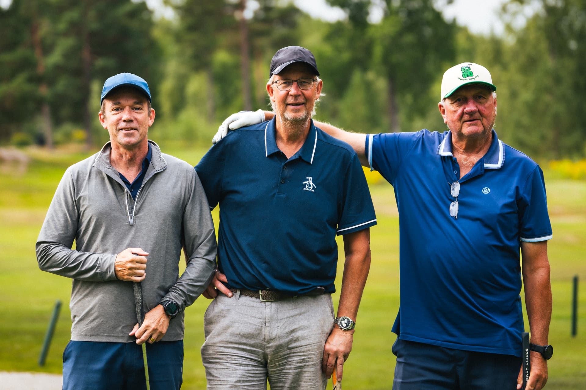 Tre spelare i blått poserar på tee