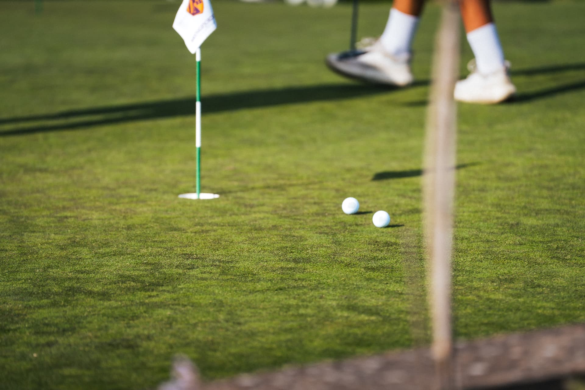Två golfbollar på greenen intill flaggan