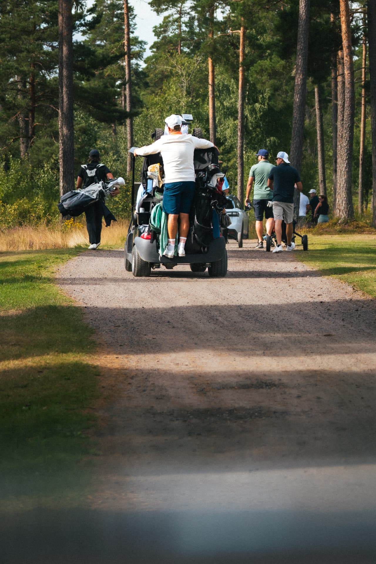 Spelare åker med på golfbilen längs banvägen